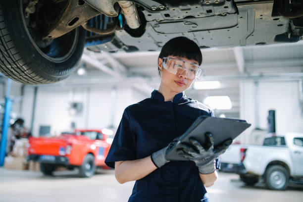 gettyimages-2117510301-612x612 Female Japanese electrician mechanic in a car repair shop, using a digital tablet, inspecting vehicles.